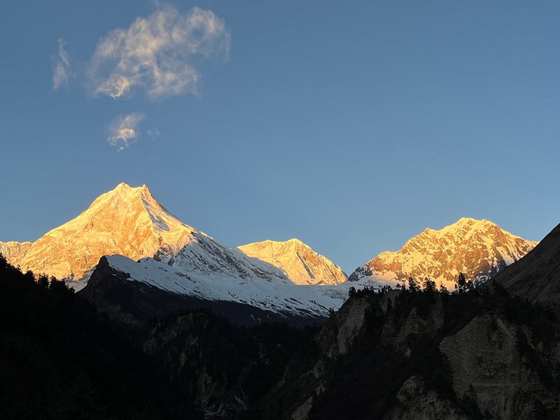 Sunset view of Manaslu from Manaslu basecamp, golden light on snow-capped peaks and rugged terrain.