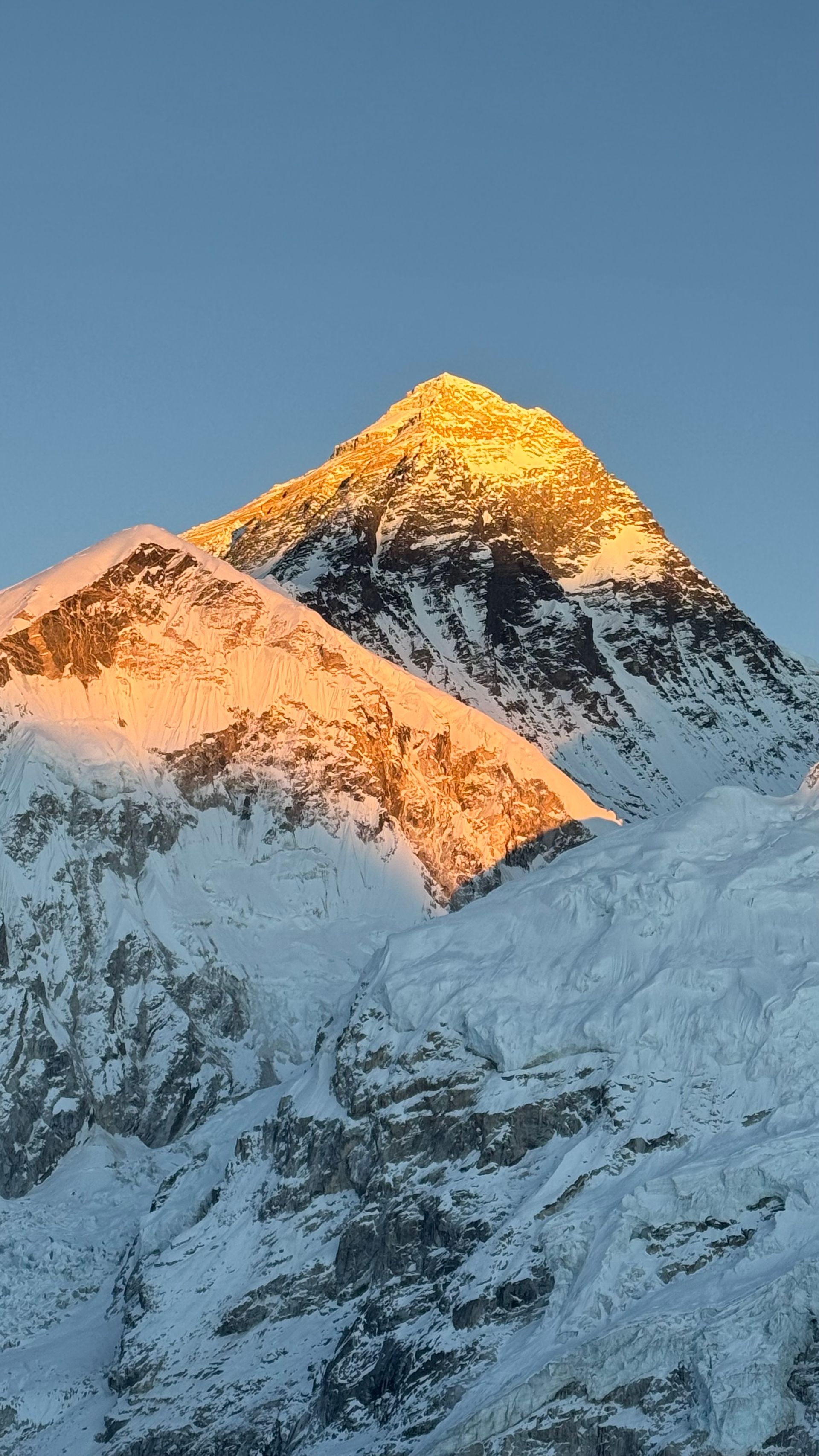 View of Mount Everest towering above the rocky landscape of Everest Base Camp, with prayer flags fluttering in the foreground.