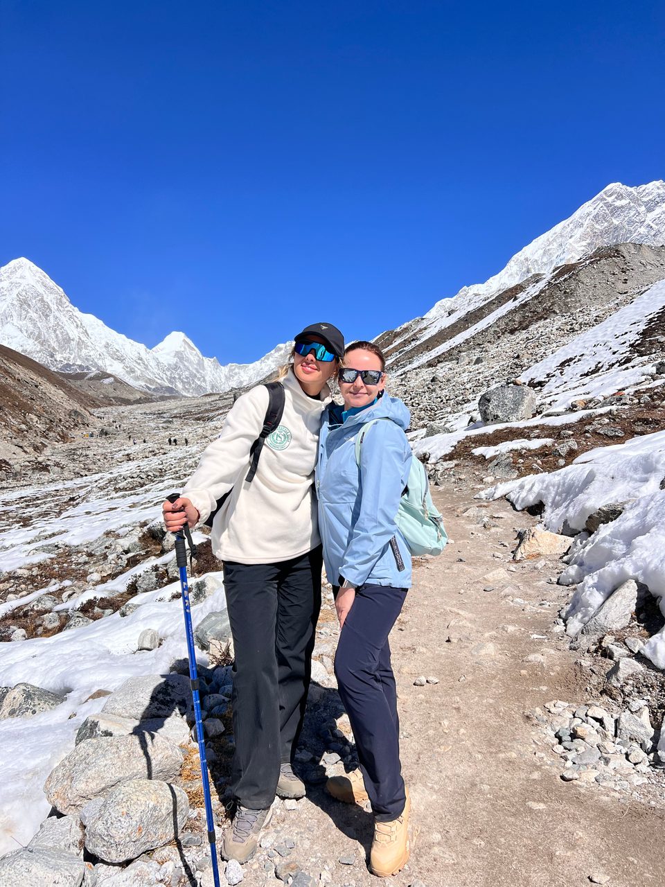 Trekkers enjoying panoramic mountain views on the Everest Base Camp trek, with snow-capped peaks and rocky terrain in the background.