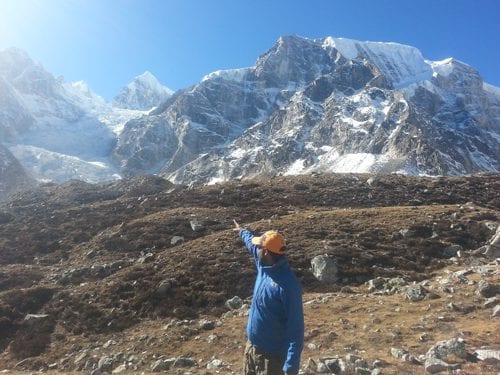 Madan pointing toward mountain passes on the trail to Larke Pass in the  12 days Manaslu circuit trek.